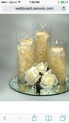 three candles are sitting on a glass plate with flowers in front of the candle holders