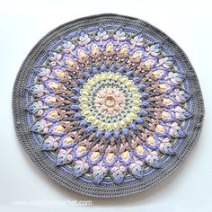 a crocheted doily is shown on a white surface with blue, yellow and pink colors