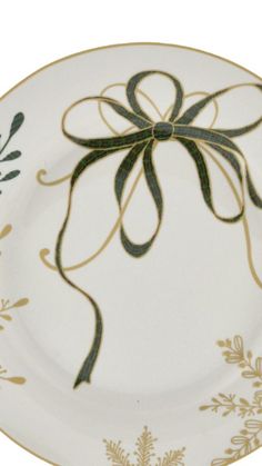 a white and gold plate with a green bow on the side, decorated with flowers