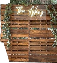 the sign is made out of wooden pallets and has greenery on it's sides