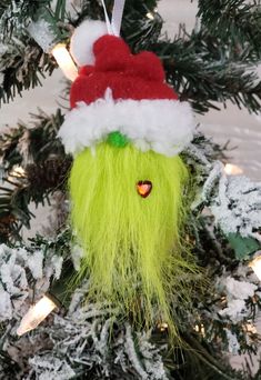 an ornament hanging from a christmas tree decorated with green hair and a santa hat