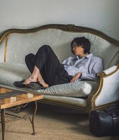 a woman laying on top of a couch next to a table