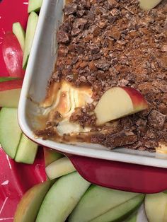 an apple dessert in a red dish surrounded by sliced apples