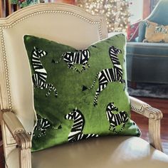 a green pillow with zebras on it sitting on a chair in front of a christmas tree