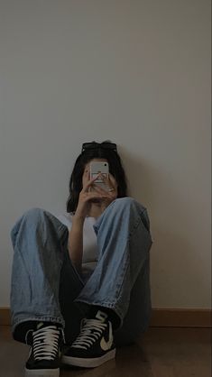 a woman sitting on the floor taking a photo with her cell phone