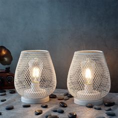 two lit candles sitting next to each other on top of a table covered in rocks