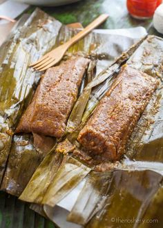 two pieces of cooked fish sitting on top of foil with a fork next to it