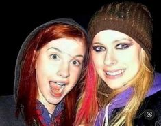 two young women are posing for the camera with their tongue out and one is wearing a beanie