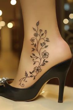 a woman's foot with a flower tattoo on the side of her shoe, which is decorated with leaves and flowers