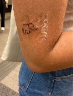 an elephant tattoo on the back of a woman's left arm, which is drawn in black ink