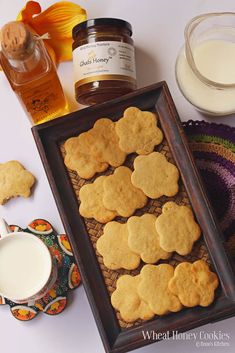 some cookies are on a tray next to honey and a glass of milk in the background