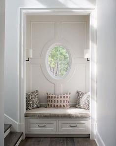 a window seat in the entry way of a house with white walls and wood flooring