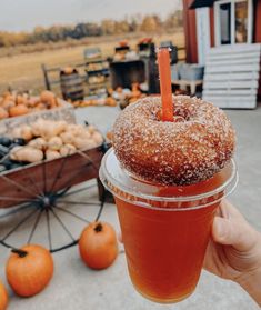 a person holding up a drink in front of some pumpkins