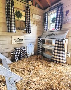 a chicken coop with hay in the floor and black and white checkered curtains on the windows