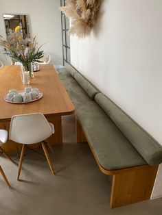 a wooden table with two white chairs next to it and a bench on the side