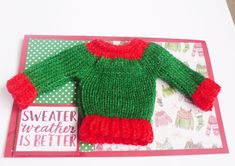 a green and red sweater on top of a card