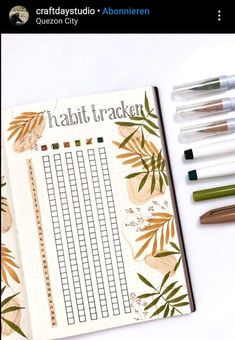 an open planner with pens and markers next to it