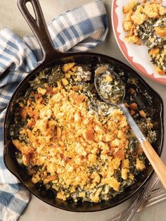 a skillet with some food in it on a table next to a plate and spoon