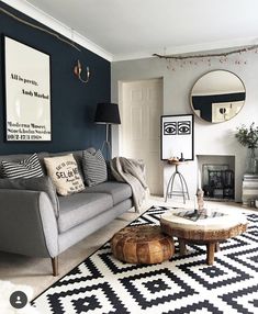 a living room with blue walls and black and white rugs on the floor next to a gray couch