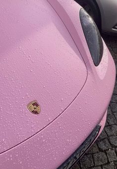 a pink sports car is parked on the side of the road with water droplets all over it