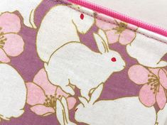 "This zipper pouch is made from Japanese cotton print. It is 100% cotton imported from Japan. This bag features white bunnies and a pink camellia on a lavender background with a metallic gold embellishments. Fully lined with Japanese cotton fabric of a pink with a pin dot pattern. Zipper is hot pink and the zipper pull is accessorized with a gold flower shaped charm. Perfect purse for keeping small items such as compact digital camera, iPod, credit cards, etc. Dimensions (approx): 3.5\"L x 5\"W White Zipper Pouch Pencil Case, White Rectangular Pouch With Zipper Pocket, White Zipper Pouch For Personal Use, White Rectangular Zipper Pouch, White Pencil Case With Zipper, White Rectangular Pouch With Pen Holders, White Zipper Pouch Pencil Case For Daily Use, White Pouch With Pen Slots For Daily Use, White Cosmetic Bag With Pen Slots For Personal Use