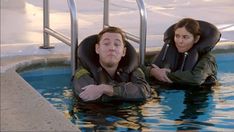 a man and woman sitting in a swimming pool