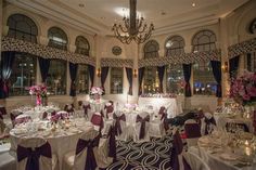 the banquet room is decorated with white linens and purple sashes, along with floral centerpieces