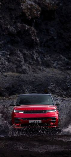 a red car is driving through some water