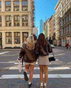 two women walking across a cross walk in the city