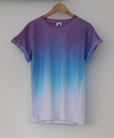 a purple and blue t - shirt hanging up on a wall next to a wooden hanger