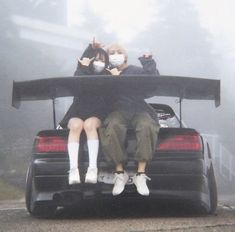 two people sitting on the back of a car