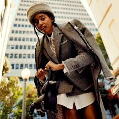 a woman in a suit and hat holding an umbrella