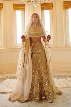 a woman in a gold and white bridal gown standing next to a chandelier