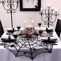 a dining room table decorated for halloween with skulls and spider webs on the table