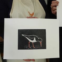 two people holding up some artwork with birds on them