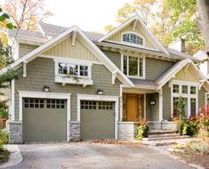 a gray house with white trim and two car garages on the front door is surrounded by trees