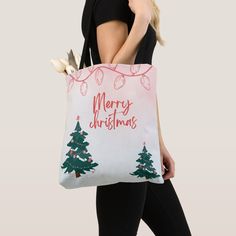 a woman carrying a christmas shopping bag with trees and lights on the front, while wearing black leggings