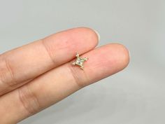 a person's hand holding a tiny diamond ring