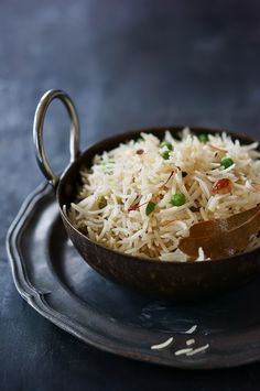 a bowl filled with rice and peas on top of a metal plate next to a spoon