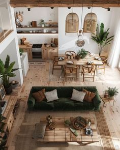 an overhead view of a living room and dining area with green couches, coffee table, potted houseplant and kitchen in the background