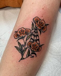 a close up of a person's leg with tattoos on it and flowers in the middle