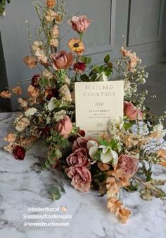 an arrangement of flowers on a table with a sign that says,'beautiful goats '