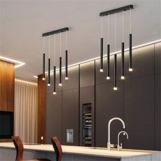 a modern kitchen with an island and bar stools in the center, lights hanging from the ceiling