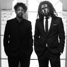 two men dressed in suits and ties standing next to each other with dreadlocks