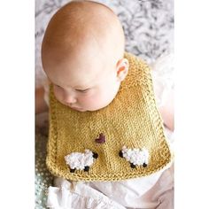 a baby wearing a knitted bib with sheeps on it's side