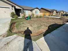 the shadow of a person standing in front of a house on a lawn with grass