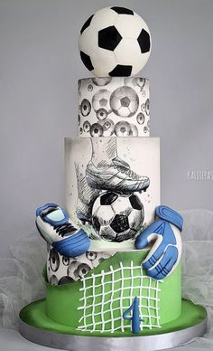 a three tiered cake with a soccer theme on it's side and blue gloves