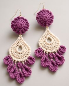 two pairs of crocheted earrings on a white table with purple and white beads