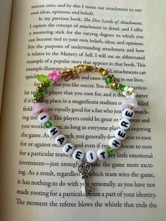 an open book with a key charm on it and some beads hanging from the end