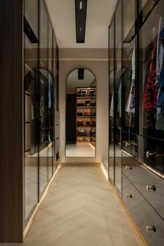 an empty walk in closet with mirrored walls and drawers on both sides that are illuminated by recessed lights